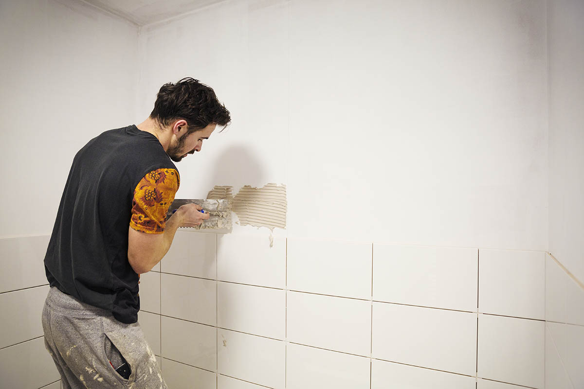 man in surrey tiling a bathroom wall