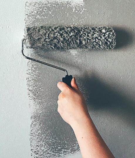 woman painting wall with paint roller