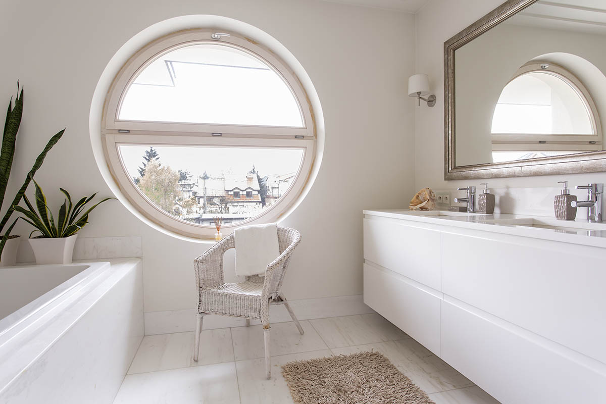 beautiful bathroom with round window and chair