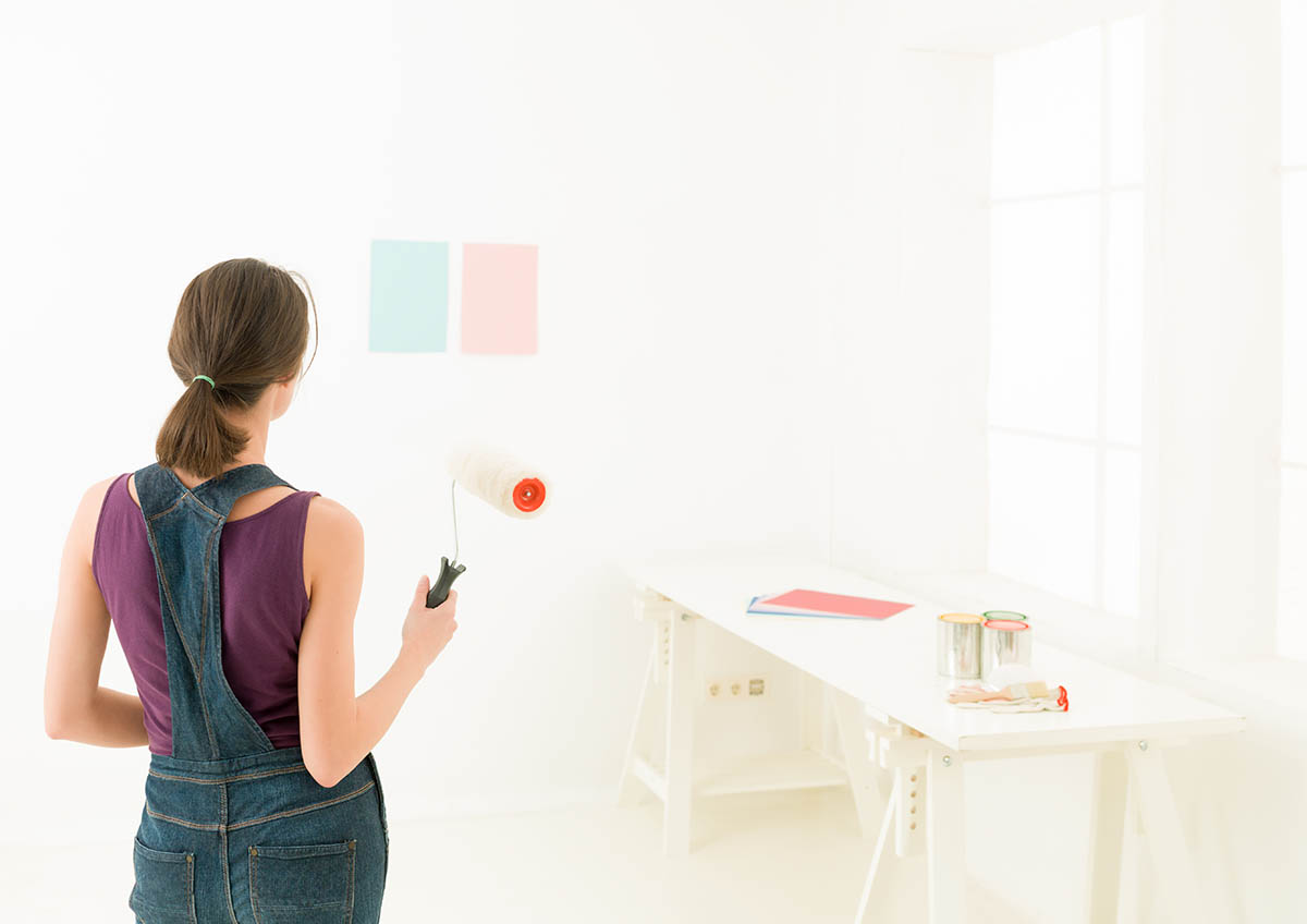 woman comparing colours on wall before painting interior walls